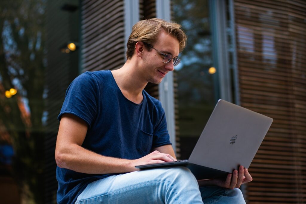 Student schaut glücklich auf seinen Laptop Warum sich ein Auslandsstudium für Sie lohnen könnte